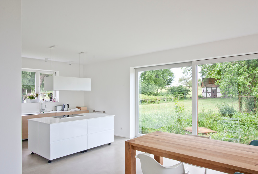 Exempel på ett modernt kök och matrum, med släta luckor, vita skåp, en köksö, en enkel diskho och vitt stänkskydd