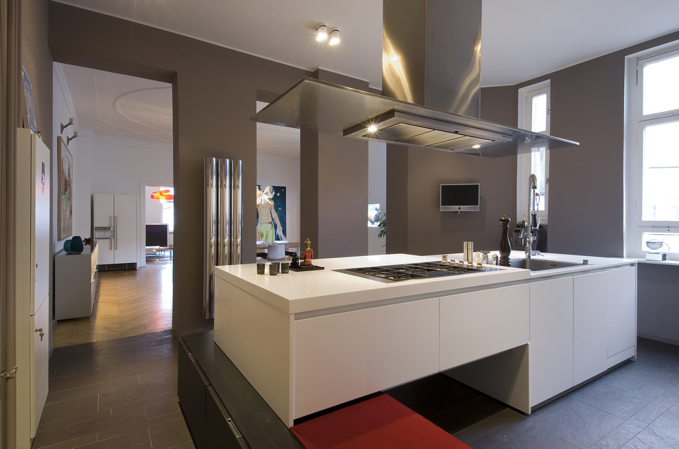 Offene, Mittelgroße Moderne Küche in grau-weiß mit flächenbündigen Schrankfronten, Küchengeräten aus Edelstahl, Einbauwaschbecken, weißen Schränken, Schieferboden und Kücheninsel in Berlin