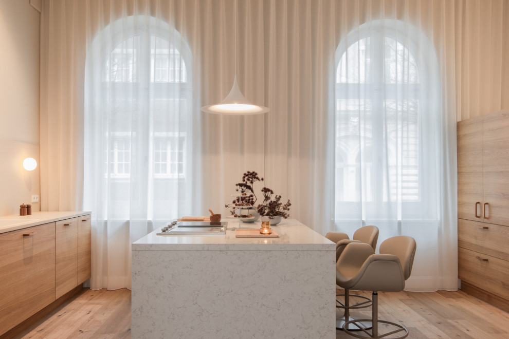 Immagine di un cucina con isola centrale nordico con ante lisce, ante in legno chiaro, paraspruzzi bianco, parquet chiaro, pavimento beige, top bianco e top in marmo