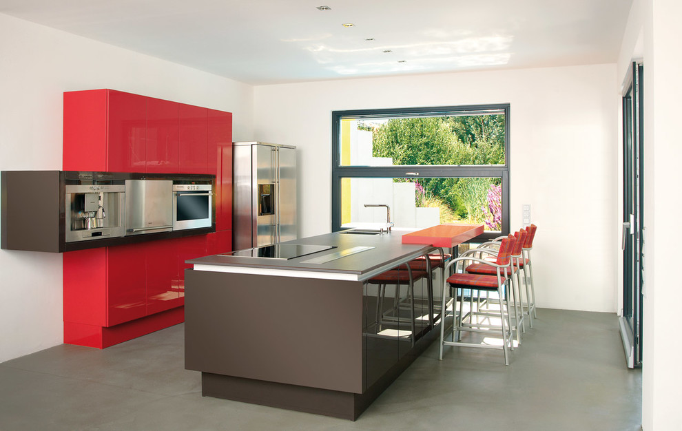 Geschlossene, Große Moderne Küche mit Doppelwaschbecken, flächenbündigen Schrankfronten, roten Schränken, Küchengeräten aus Edelstahl und Kücheninsel in Nürnberg