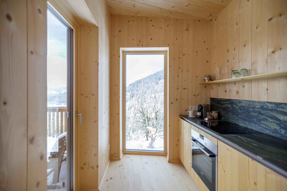 Exemple d'une petite cuisine linéaire scandinave en bois brun fermée avec un placard à porte plane, un plan de travail en onyx, une crédence multicolore, un électroménager en acier inoxydable, parquet clair, aucun îlot et un sol beige.