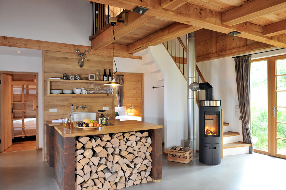 Example of a mid-sized mountain style single-wall concrete floor open concept kitchen design in Other with a farmhouse sink, an island, wood countertops, open cabinets and medium tone wood cabinets