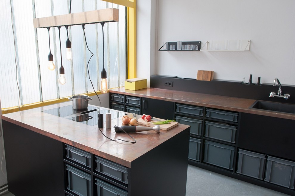 Design ideas for a medium sized contemporary single-wall open plan kitchen in Berlin with a built-in sink, black cabinets, copper worktops, white splashback, black appliances, concrete flooring and an island.