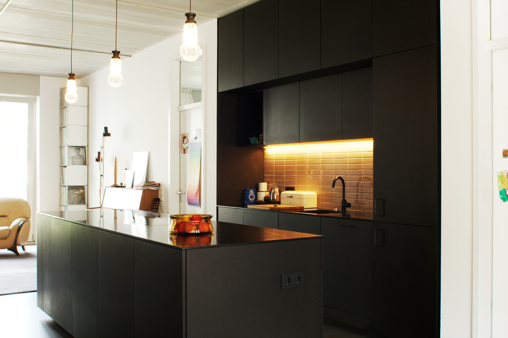 Moderne Küche mit schwarzen Schränken, Mineralwerkstoff-Arbeitsplatte, schwarzen Elektrogeräten und Kücheninsel in Berlin