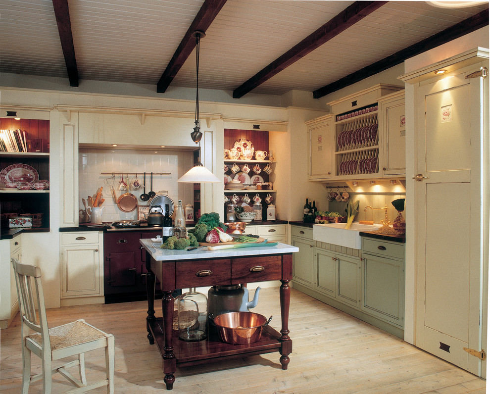Lantlig inredning av ett mellanstort l-kök, med en rustik diskho, luckor med profilerade fronter, gröna skåp, träbänkskiva, grönt stänkskydd, färgglada vitvaror, ljust trägolv och en köksö