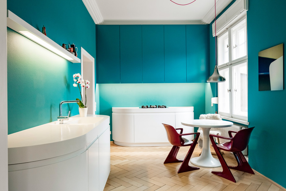 Идея дизайна: параллельная кухня среднего размера в стиле модернизм с монолитной мойкой, плоскими фасадами, синими фасадами, столешницей из акрилового камня, синим фартуком и светлым паркетным полом без острова