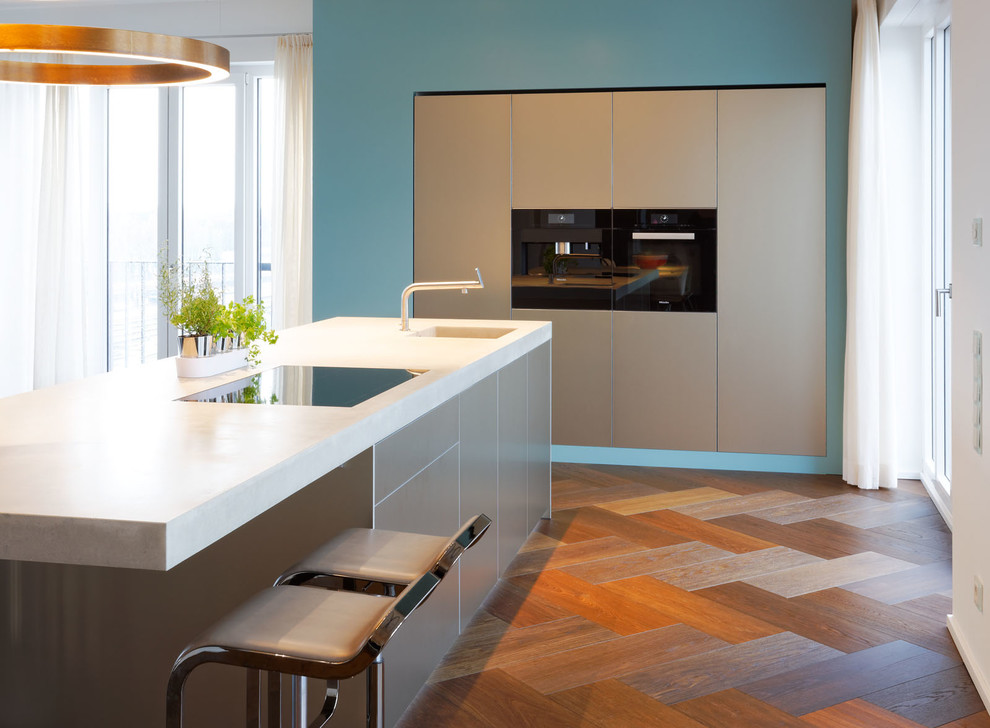 Idee per una cucina moderna di medie dimensioni con lavello integrato, ante lisce, ante beige, top in cemento, elettrodomestici neri e parquet scuro