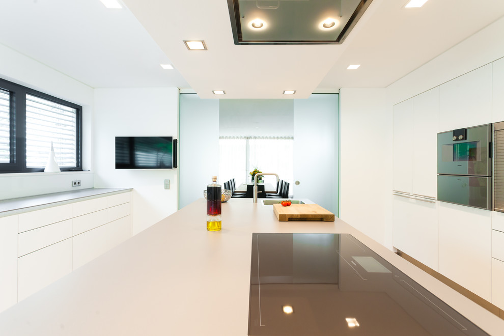 Offene, Einzeilige Moderne Küche mit weißen Schränken, Küchenrückwand in Weiß, Küchengeräten aus Edelstahl und Kücheninsel in Frankfurt am Main