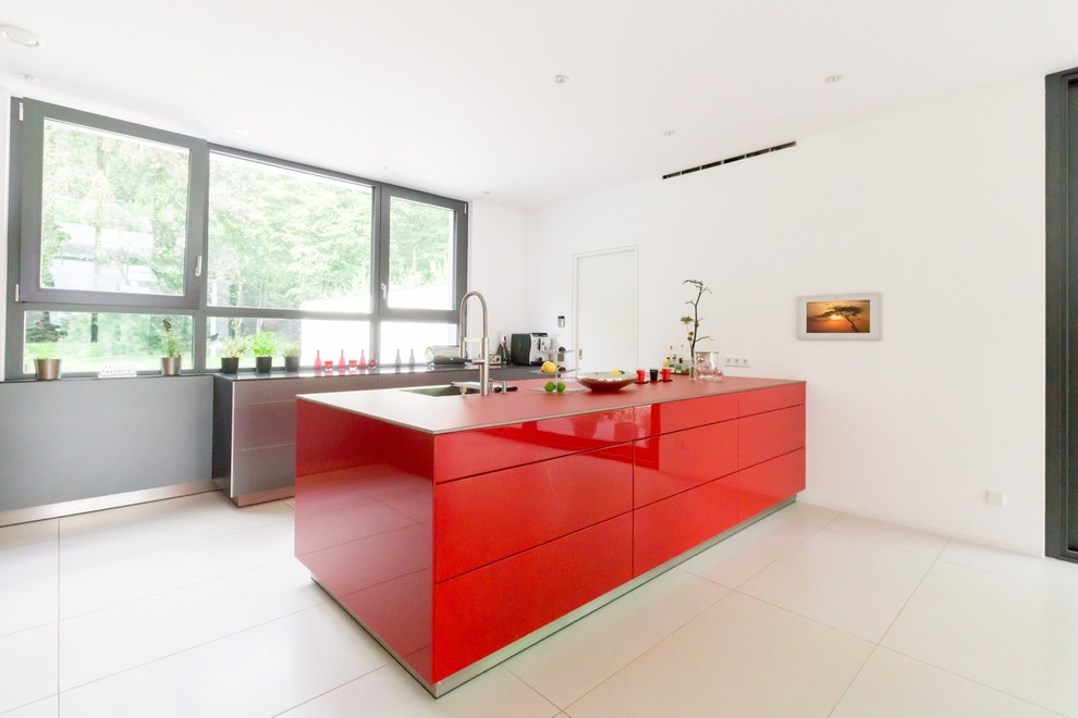 Moderne Küche mit Waschbecken, flächenbündigen Schrankfronten, roten Schränken und Halbinsel in Stuttgart