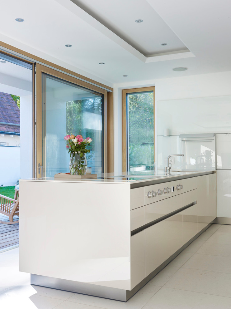 Large trendy kitchen photo in Munich with flat-panel cabinets, beige cabinets, white backsplash, glass sheet backsplash, paneled appliances and a peninsula