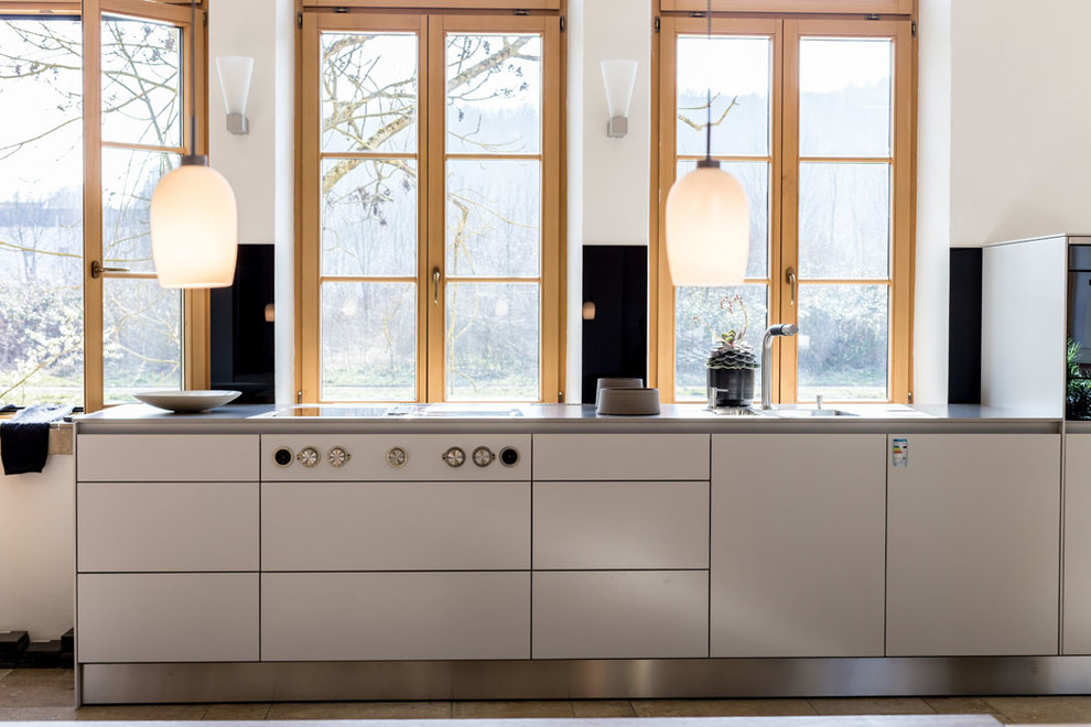 Imagen de cocina lineal contemporánea de tamaño medio sin isla con armarios con paneles lisos, puertas de armario blancas, salpicadero negro, salpicadero de vidrio templado y fregadero integrado