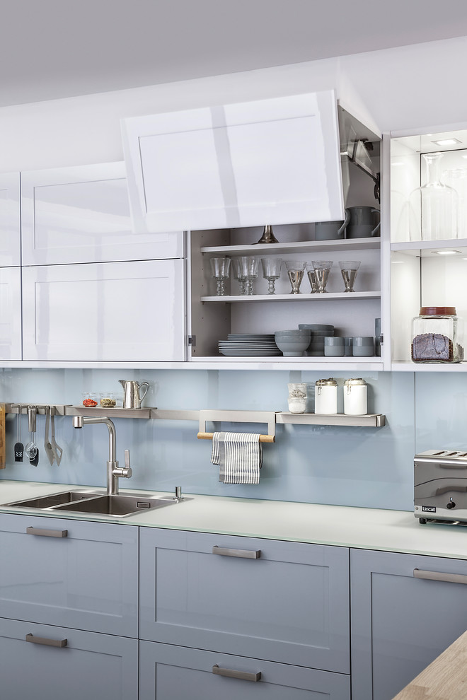 Immagine di una cucina design con lavello da incasso, ante in stile shaker, paraspruzzi grigio, paraspruzzi con lastra di vetro, elettrodomestici in acciaio inossidabile e ante blu