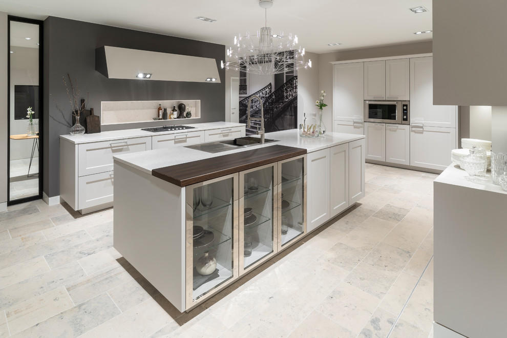 Large traditional galley open plan kitchen in Cologne with an integrated sink, white cabinets, grey splashback, stainless steel appliances, an island, beige floors, white worktops and shaker cabinets.