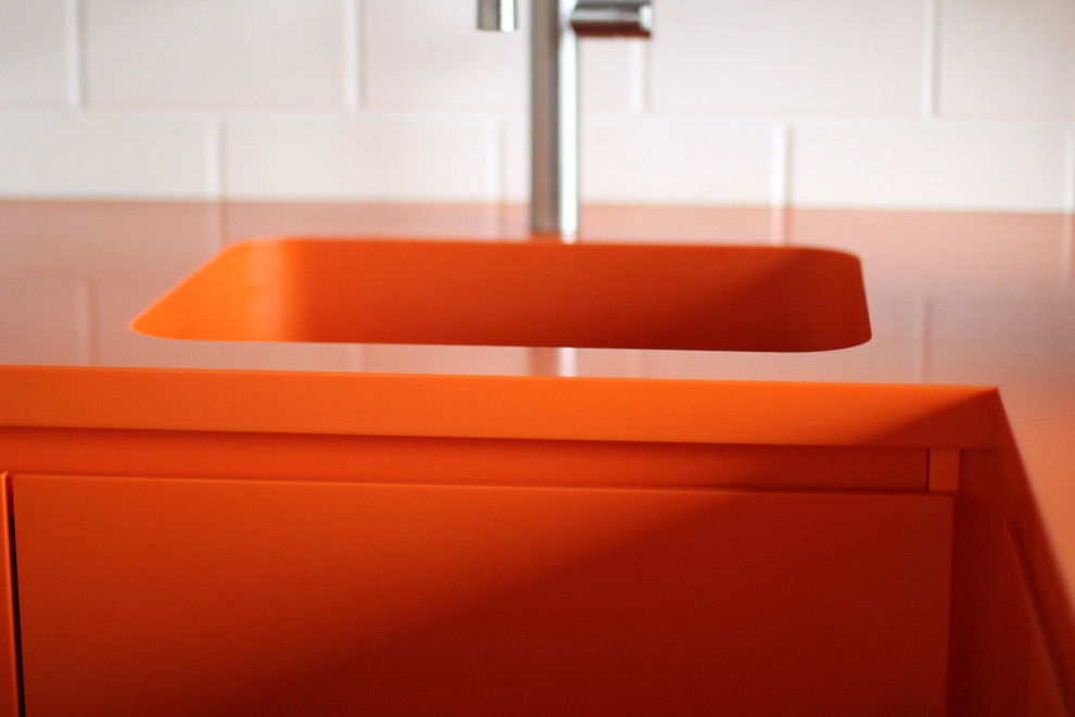Idéer för mellanstora funkis oranget kök, med en undermonterad diskho, släta luckor, orange skåp, bänkskiva i koppar, svarta vitvaror och grått golv