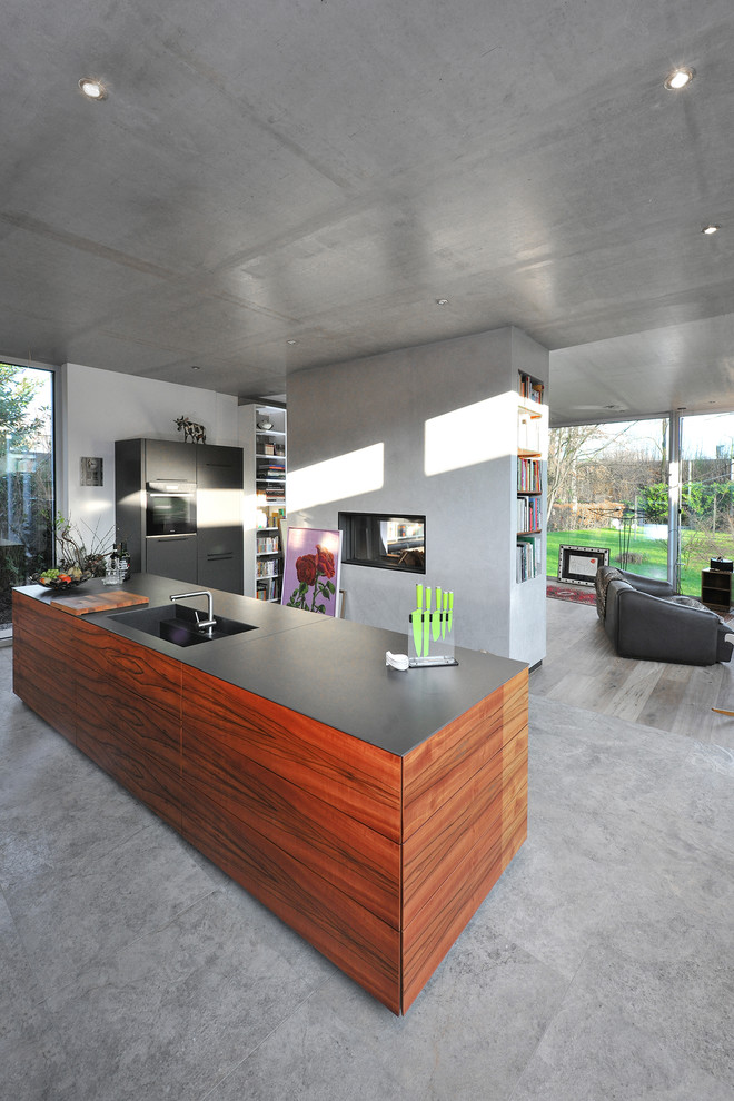 Foto di una cucina minimal di medie dimensioni con lavello a vasca singola, ante lisce, ante in legno scuro, top in granito, pavimento in travertino, pavimento grigio e top grigio