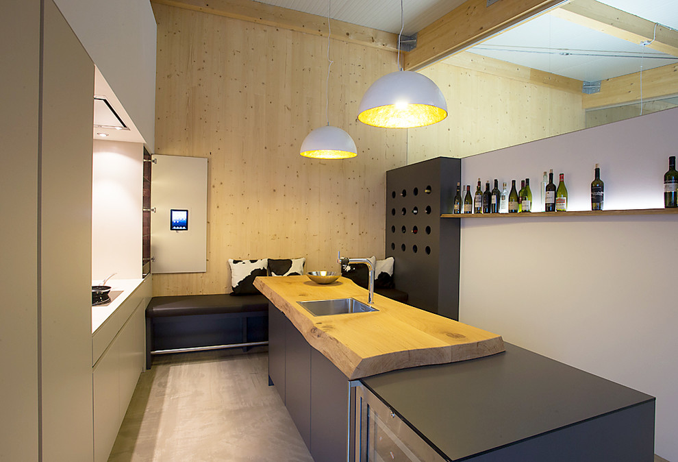 Moderne Küche mit flächenbündigen Schrankfronten, grauen Schränken, Arbeitsplatte aus Holz, bunter Rückwand, Glasrückwand, schwarzen Elektrogeräten und Kücheninsel in München