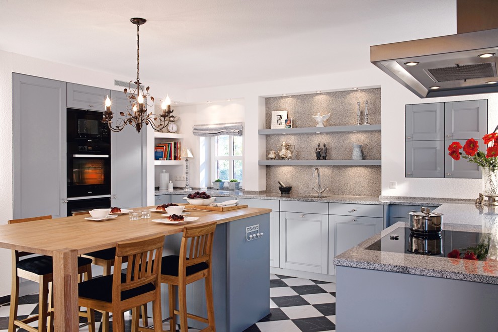 This is an example of a medium sized classic u-shaped enclosed kitchen in Berlin with a submerged sink, beaded cabinets, blue cabinets, granite worktops, grey splashback, stone slab splashback, integrated appliances, ceramic flooring and an island.