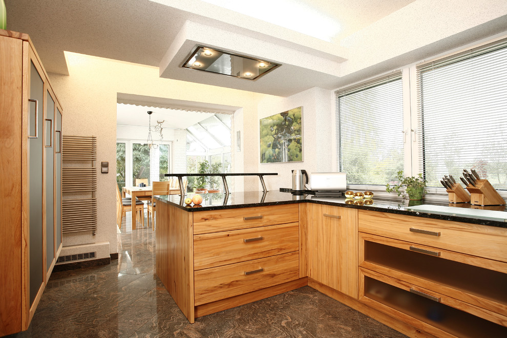 Aménagement d'une cuisine ouverte encastrable contemporaine en bois brun de taille moyenne avec un placard à porte plane, un plan de travail en granite, un sol en calcaire et une péninsule.