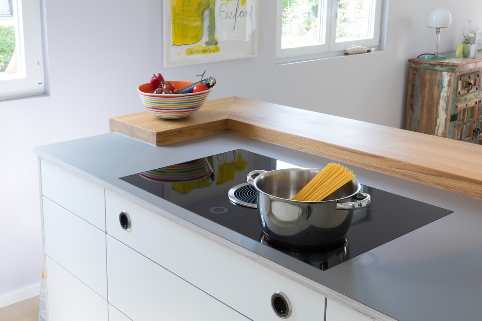 Immagine di una grande cucina design con ante lisce, ante bianche, top grigio, lavello a doppia vasca, elettrodomestici neri, parquet chiaro e pavimento marrone
