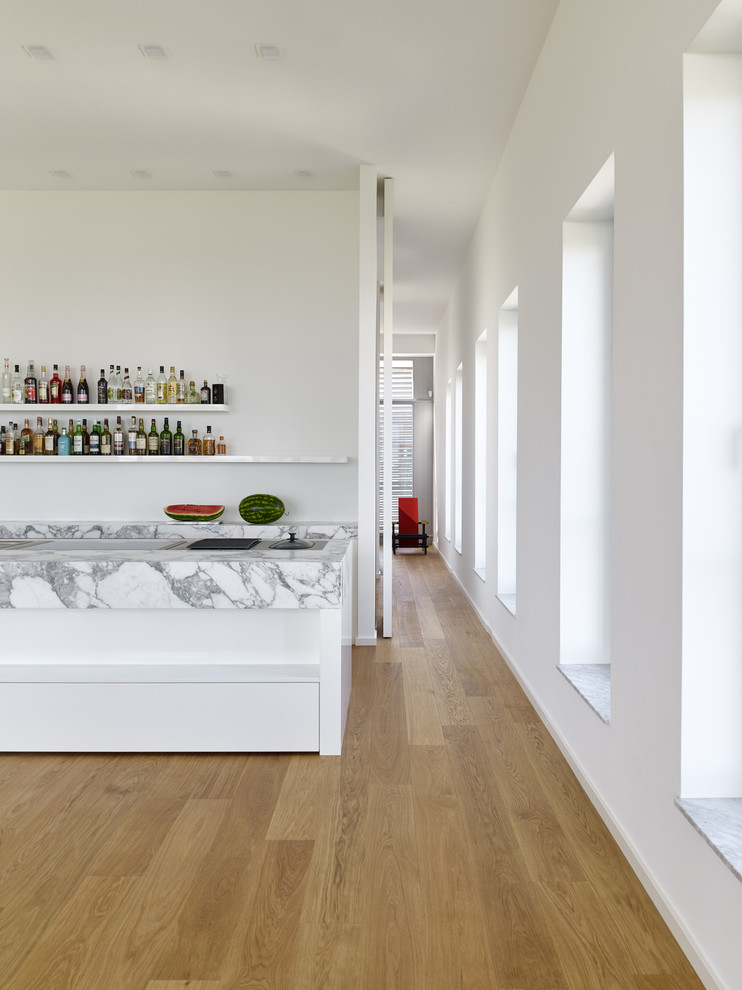 Idee per una cucina minimalista con lavello integrato, ante bianche, top in marmo, elettrodomestici in acciaio inossidabile e pavimento in legno massello medio