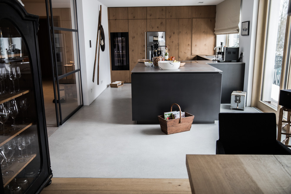 Idee per una cucina minimal di medie dimensioni con ante lisce, elettrodomestici neri, pavimento in cemento, penisola, pavimento grigio e top grigio