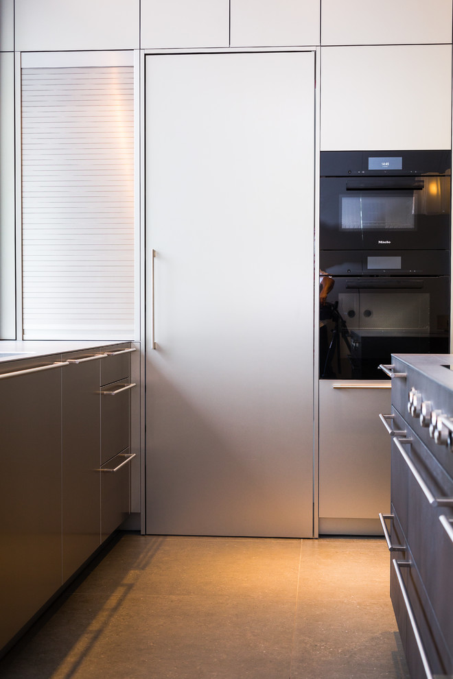 Idéer för stora funkis linjära grått kök med öppen planlösning, med en integrerad diskho, släta luckor, skåp i rostfritt stål, bänkskiva i rostfritt stål, stänkskydd med metallisk yta, rostfria vitvaror och en köksö