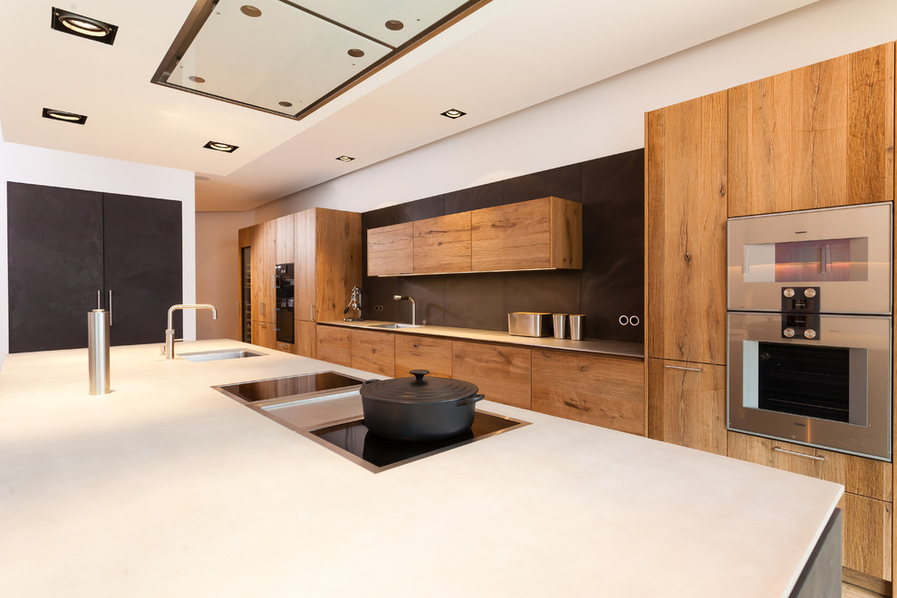 Идея дизайна: прямая кухня-гостиная в современном стиле с фасадами цвета дерева среднего тона, черным фартуком, техникой из нержавеющей стали и островом