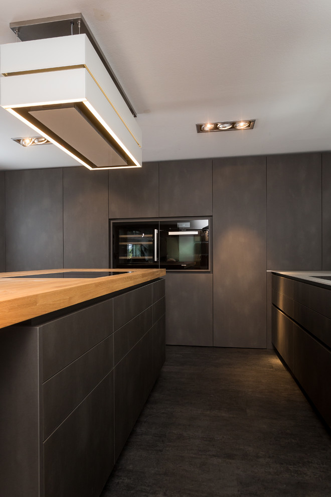 Photo of a large contemporary l-shaped open plan kitchen in Frankfurt with flat-panel cabinets, black cabinets, composite countertops, black splashback, black appliances, slate flooring, an island, grey floors and grey worktops.