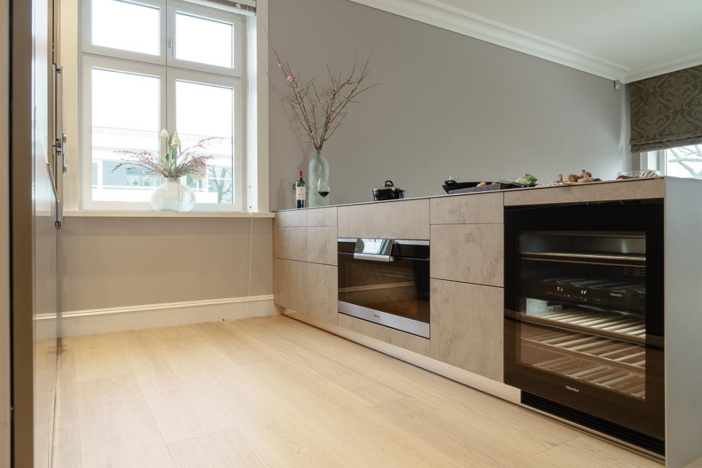 Large modern kitchen/diner in Hamburg with flat-panel cabinets, stainless steel worktops, light hardwood flooring, a breakfast bar and a submerged sink.