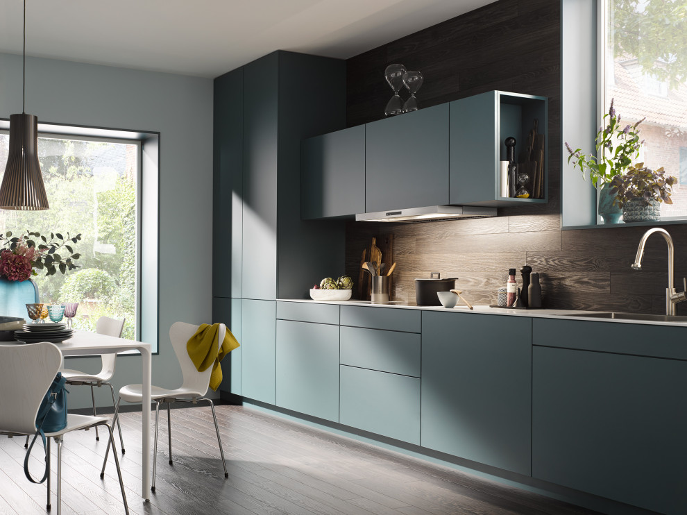Modelo de cocina lineal contemporánea abierta sin isla con puertas de armario azules, salpicadero marrón y encimeras blancas