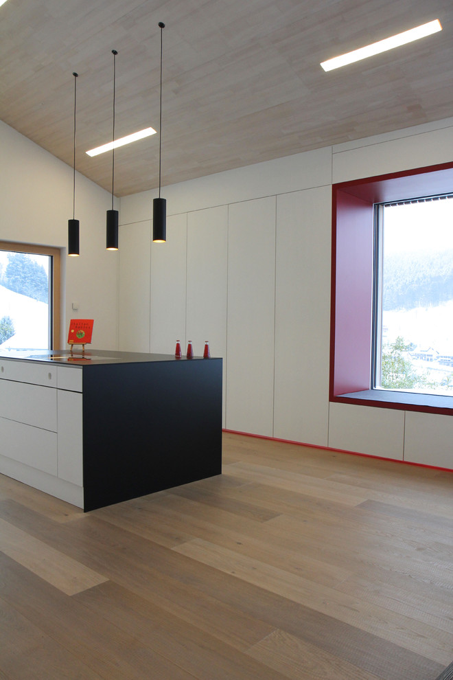 Idee per un cucina con isola centrale minimalista con ante lisce, ante bianche, pavimento in legno massello medio e pavimento marrone