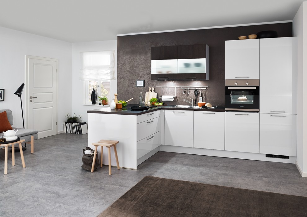 Exempel på ett mellanstort modernt brun brunt kök, med släta luckor, vita skåp, brunt stänkskydd, svarta vitvaror, betonggolv, en halv köksö, grått golv, granitbänkskiva och stänkskydd i skiffer