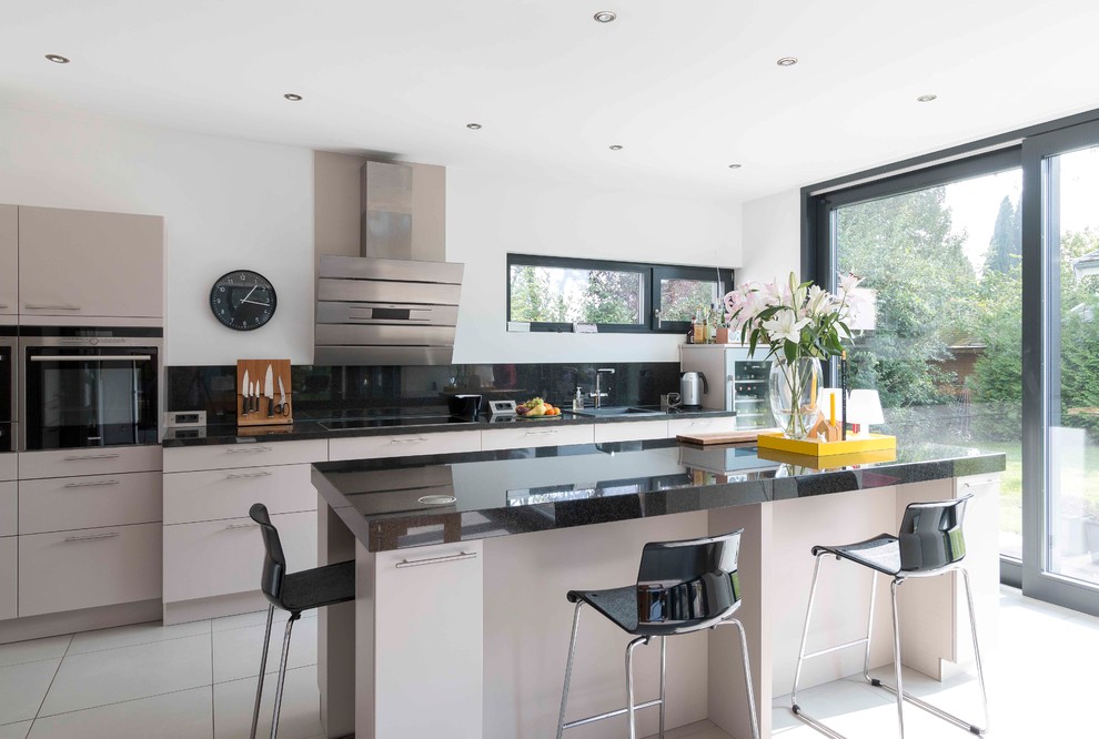 Immagine di una cucina minimal con lavello da incasso, ante lisce, ante grigie, elettrodomestici in acciaio inossidabile, pavimento bianco e top nero