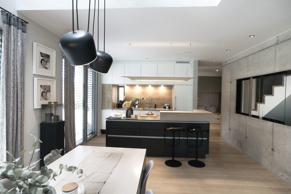 Inspiration for a medium sized urban galley open plan kitchen in Munich with an integrated sink, flat-panel cabinets, white cabinets, wood worktops, brown splashback, wood splashback, stainless steel appliances, light hardwood flooring, an island and brown worktops.