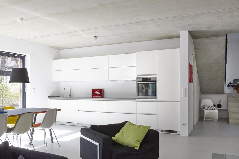 ハンブルクにある中くらいなコンテンポラリースタイルのおしゃれなキッチン (アイランドなし、フラットパネル扉のキャビネット、白いキャビネット、白いキッチンパネル、シルバーの調理設備) の写真