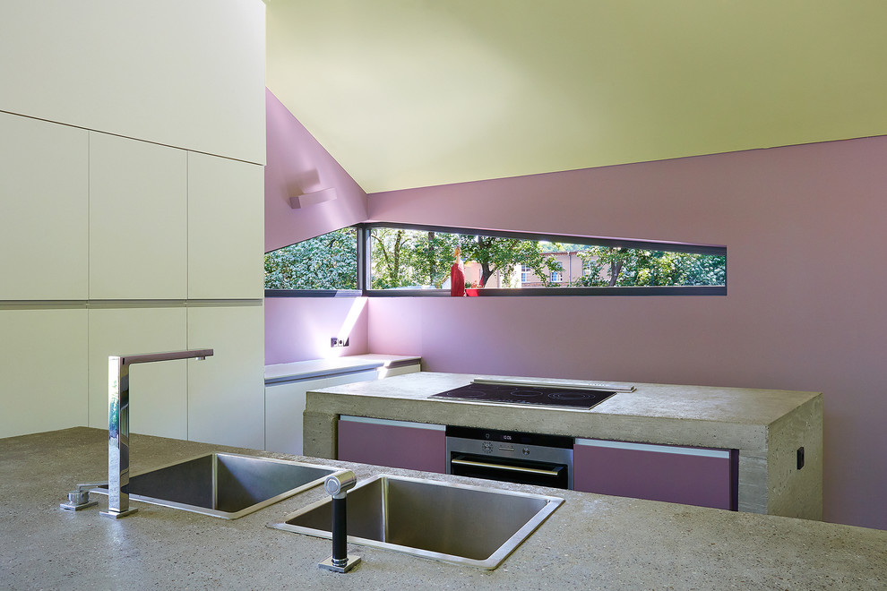 Imagen de cocina contemporánea con armarios con paneles lisos, puertas de armario violetas, encimera de cemento y una isla