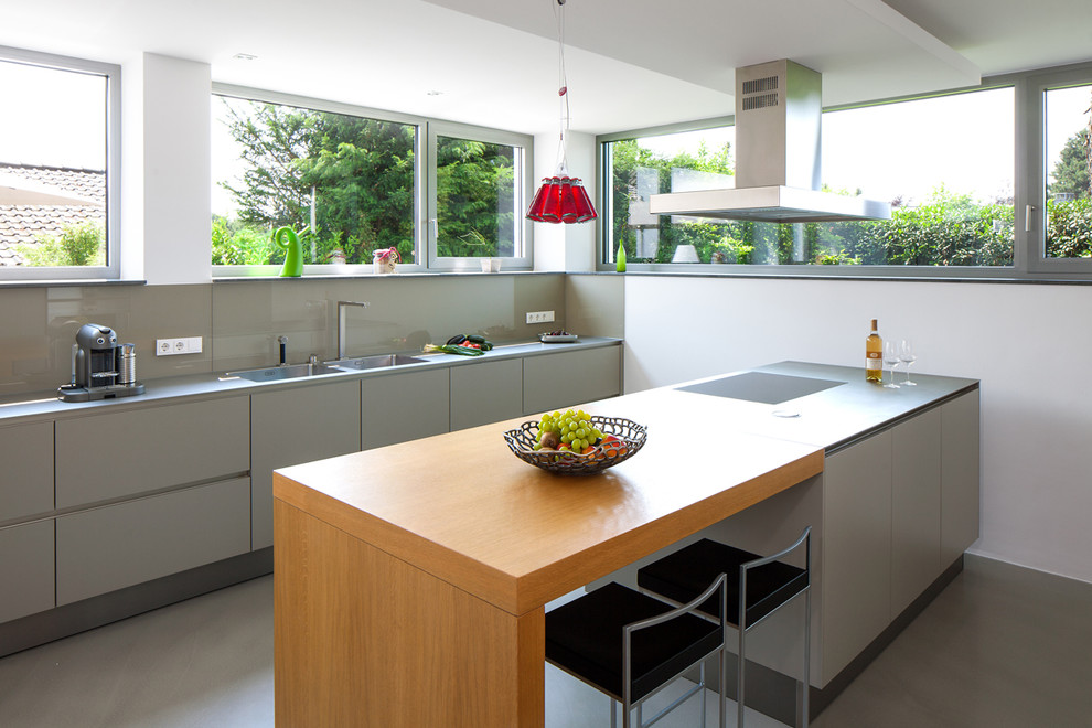 Zweizeilige Moderne Küche mit flächenbündigen Schrankfronten, grauen Schränken, Küchenrückwand in Grau, Glasrückwand und Halbinsel in Essen