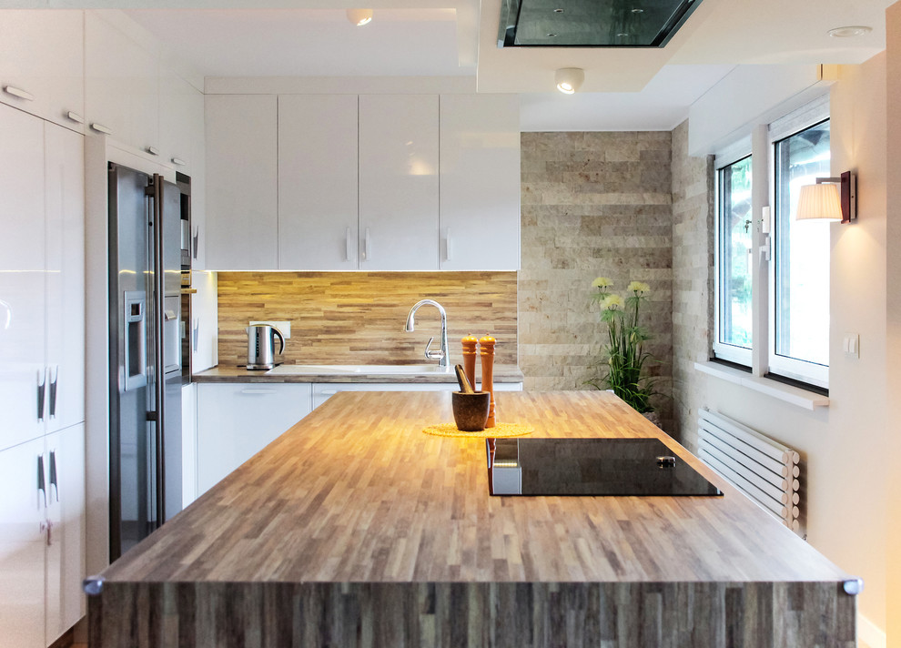 Photo of a medium sized contemporary enclosed kitchen in Berlin with an island, a built-in sink, flat-panel cabinets, white cabinets, wood worktops, brown splashback and stainless steel appliances.