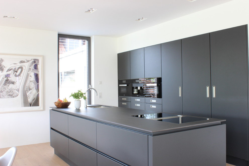Idee per una cucina minimalista con ante lisce, ante nere, pavimento in legno massello medio e pavimento marrone
