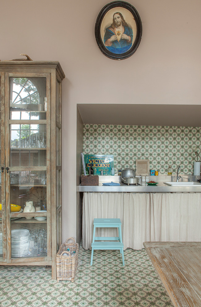 На фото: кухня в стиле фьюжн с накладной мойкой, столешницей из нержавеющей стали, полом из керамической плитки, обеденным столом, разноцветным фартуком, фартуком из керамической плитки и зеленым полом