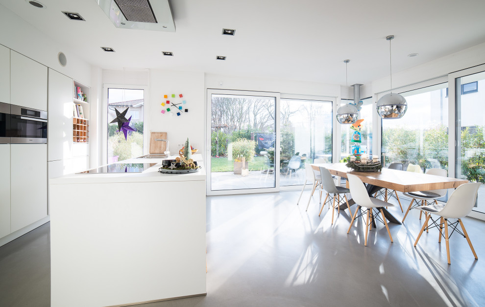 Zweizeilige Moderne Küche mit flächenbündigen Schrankfronten, weißen Schränken, Betonboden, Kücheninsel, grauem Boden und weißer Arbeitsplatte in Sonstige