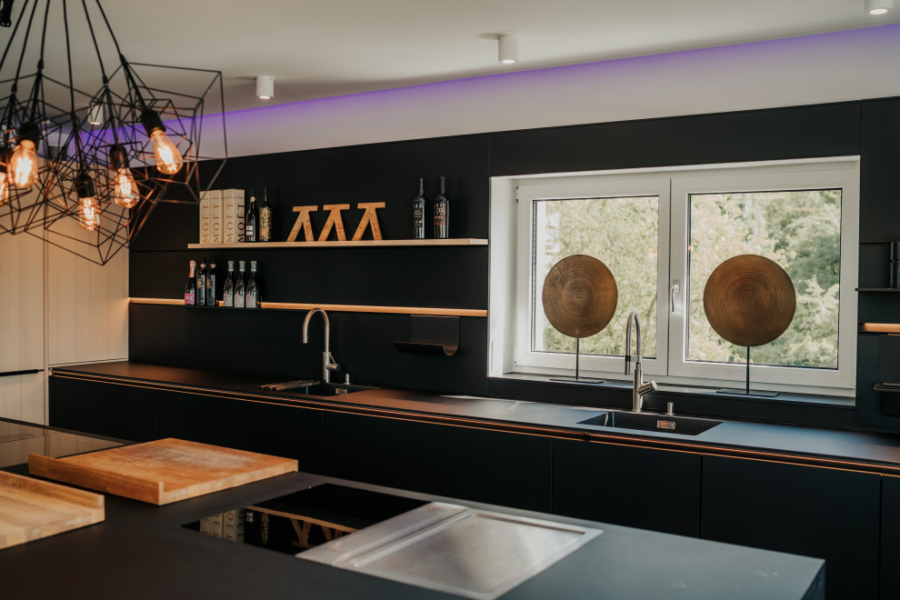 Foto på ett stort funkis svart kök, med en undermonterad diskho, släta luckor, skåp i ljust trä, bänkskiva i koppar, svart stänkskydd, svarta vitvaror, klinkergolv i keramik, en köksö och grått golv