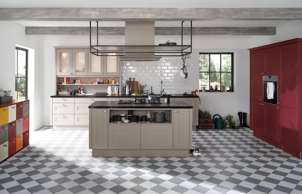 Design ideas for a traditional open plan kitchen in Hanover with a built-in sink, recessed-panel cabinets, grey cabinets, white splashback, metro tiled splashback, black appliances, an island, cement flooring and multi-coloured floors.