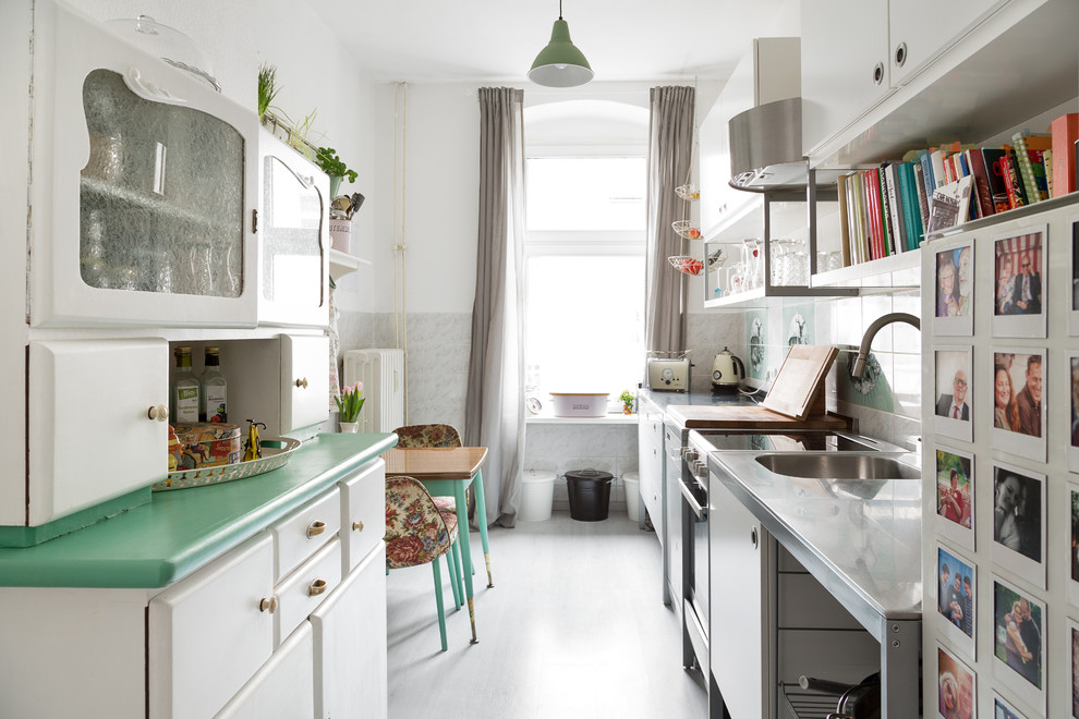 This is an example of a small romantic single-wall enclosed kitchen in Berlin with a built-in sink, flat-panel cabinets, white cabinets, stainless steel worktops, multi-coloured splashback, ceramic splashback, lino flooring and no island.