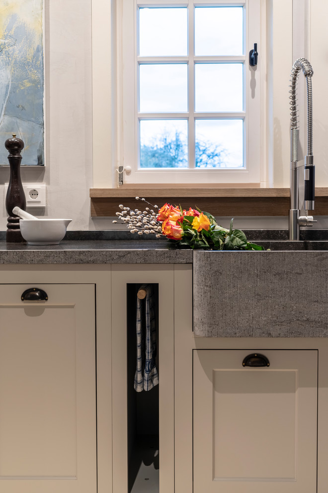 Large country single-wall open plan kitchen in Frankfurt with a double-bowl sink, beaded cabinets, grey cabinets, granite worktops, grey splashback, limestone flooring, beige floors and grey worktops.