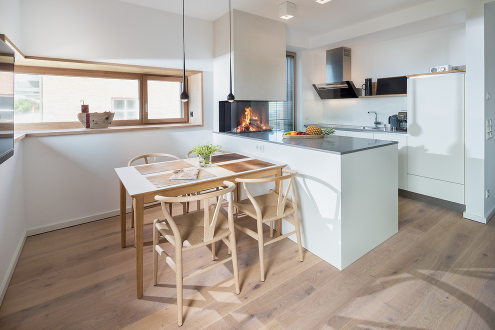 Exempel på ett litet minimalistiskt linjärt kök och matrum, med mellanmörkt trägolv, en nedsänkt diskho, släta luckor, vita skåp, vitt stänkskydd och en köksö