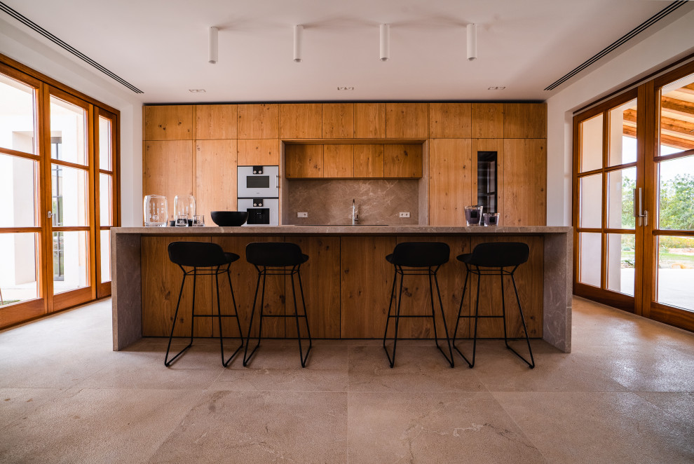 Bild på ett stort rustikt grå grått kök, med en dubbel diskho, släta luckor, skåp i mellenmörkt trä, marmorbänkskiva, grått stänkskydd, stänkskydd i marmor, rostfria vitvaror, marmorgolv, en köksö och beiget golv