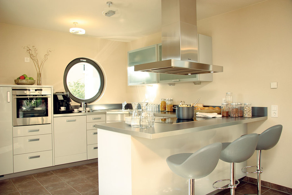 Esempio di una cucina mediterranea con ante beige, paraspruzzi beige, elettrodomestici in acciaio inossidabile, top beige, pavimento in terracotta e pavimento marrone