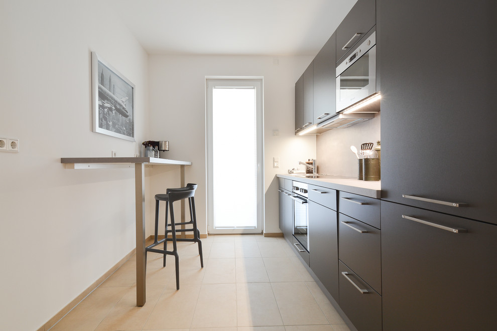 На фото: отдельная, прямая кухня среднего размера в современном стиле с плоскими фасадами, серыми фасадами и техникой под мебельный фасад без острова с