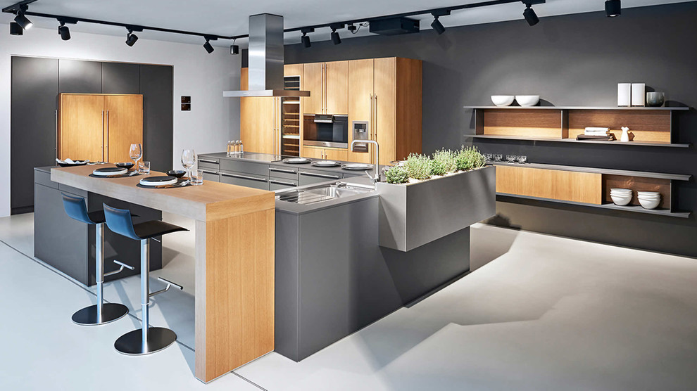 Große Moderne Küche mit Kücheninsel, flächenbündigen Schrankfronten, weißen Schränken, schwarzen Elektrogeräten und braunem Boden in Sonstige